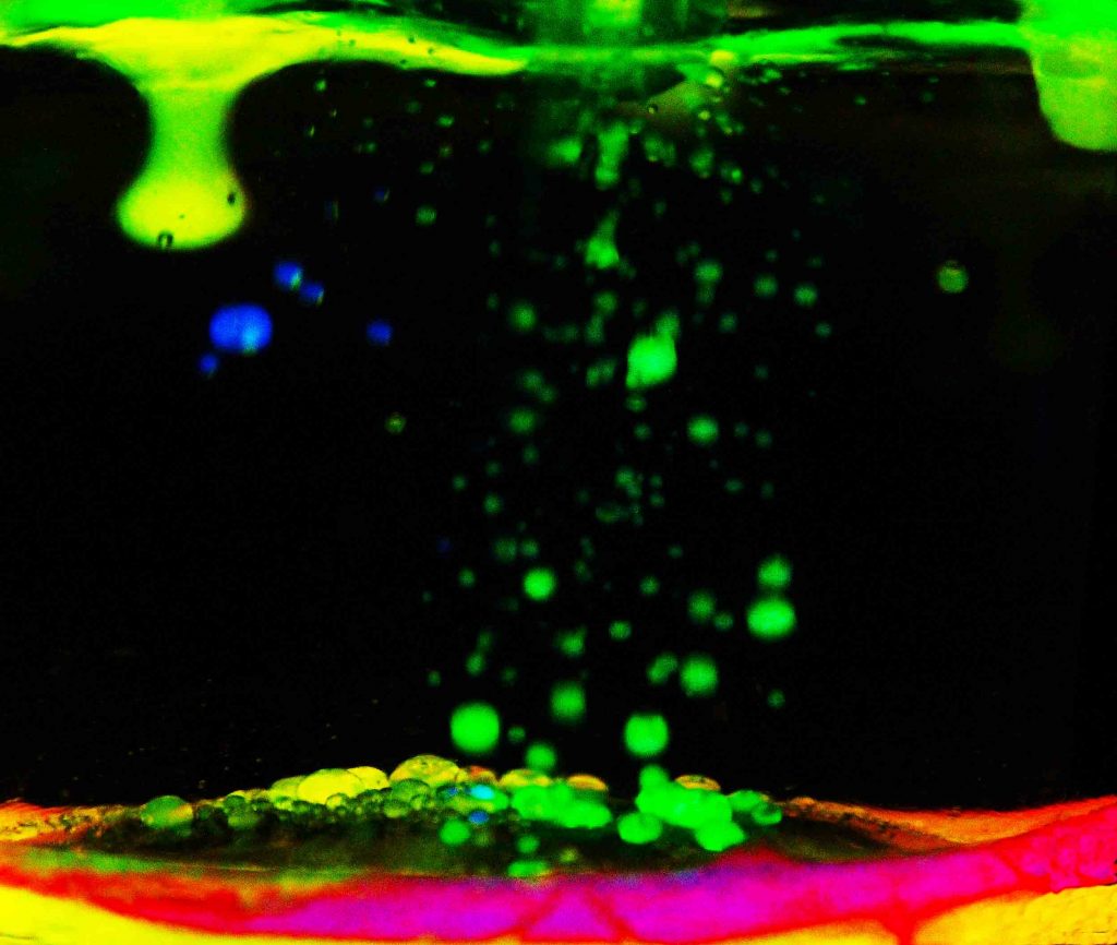 Chemiluminecent liquid from a glow stick falls in water. Flow