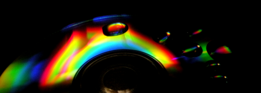 Water droplets on a CD reflect and refract the rainbow light dispersed ...
