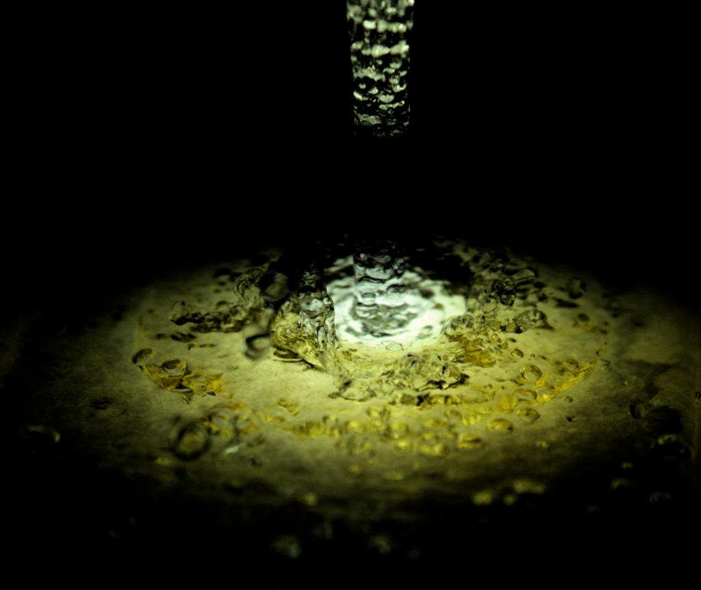 flow of water from a faucet interacting with honey on a plate below
